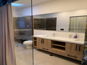Ein modernes Badezimmer mit Duschkabine aus Glas, einer weißen Toilette und Holzschränken.