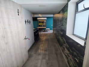 Ein Flur mit Holzboden, einer Tür mit der Aufschrift '204', einem Fenster mit Blick auf einen Wald und einer Wand mit einem Wandgemälde.