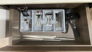 Eine Schublade mit einem Messer, einem Löffel, einer Gabel, einem Pfannenwender und einem Korkenzieher.