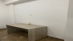 A room with a wooden desk, a small green vase with reed sticks, and a white wall with a power outlet. - Laureles Executive Suites 104 (Medellín)
