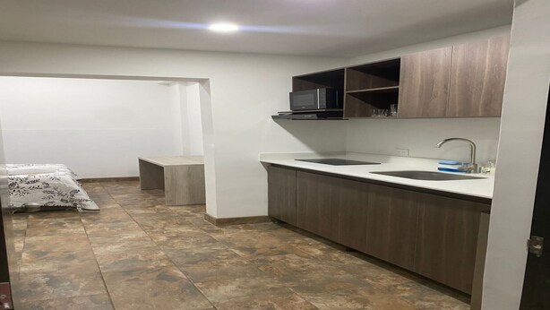 A compact kitchen with a microwave, sink, and wooden cabinets. - Laureles Executive Suites 104 (Medellín)