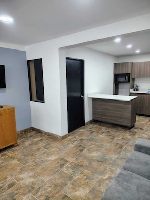 A modern kitchen with a microwave, wooden cabinets, and a grey countertop. - Laureles Executive Suites 105 (Medellín)
