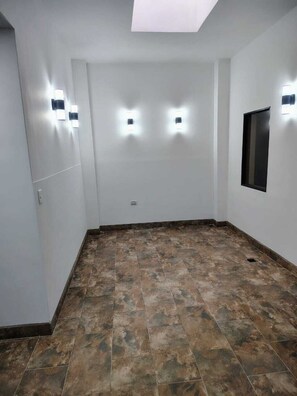 A room with a sloped ceiling, recessed lighting, a window, and a tiled floor. - Laureles Executive Suites 105 (Medellín)