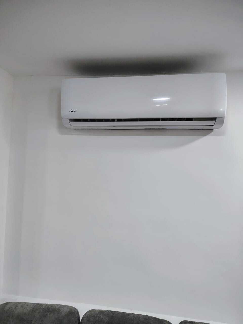 A white air conditioning unit mounted on a plain wall.