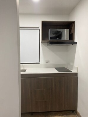 Eine kleine Küche mit Mikrowelle, Spüle und Schrank.