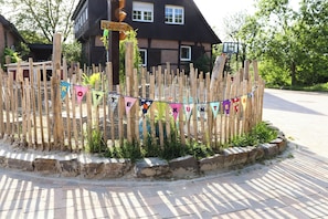 A wooden fence with colorful triangular flags, a brick border, and a house in the background.