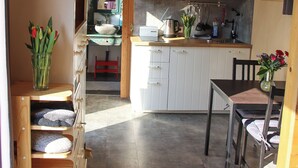 Une cuisine avec des meubles blancs, un four à micro-ondes et une machine à café. On y trouve une table à manger en bois avec des chaises.