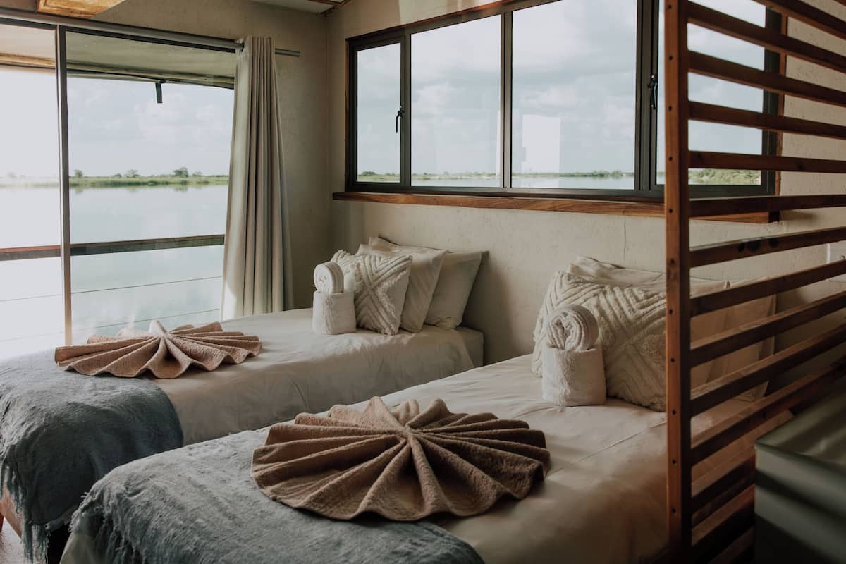 Una habitación con dos camas, una ventana con vistas al agua y una estructura de listones de madera.