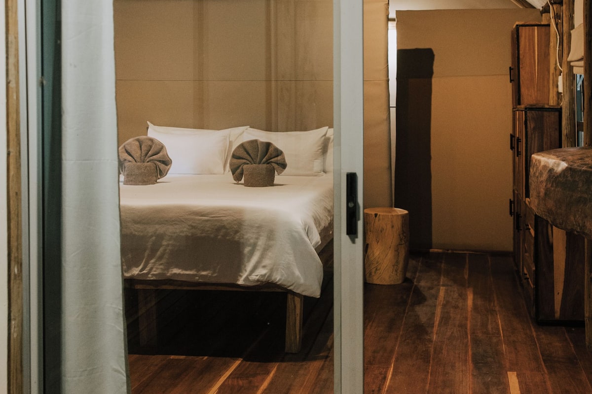 Un dormitorio con cama, piso de madera y puerta corredera que da a un baño.