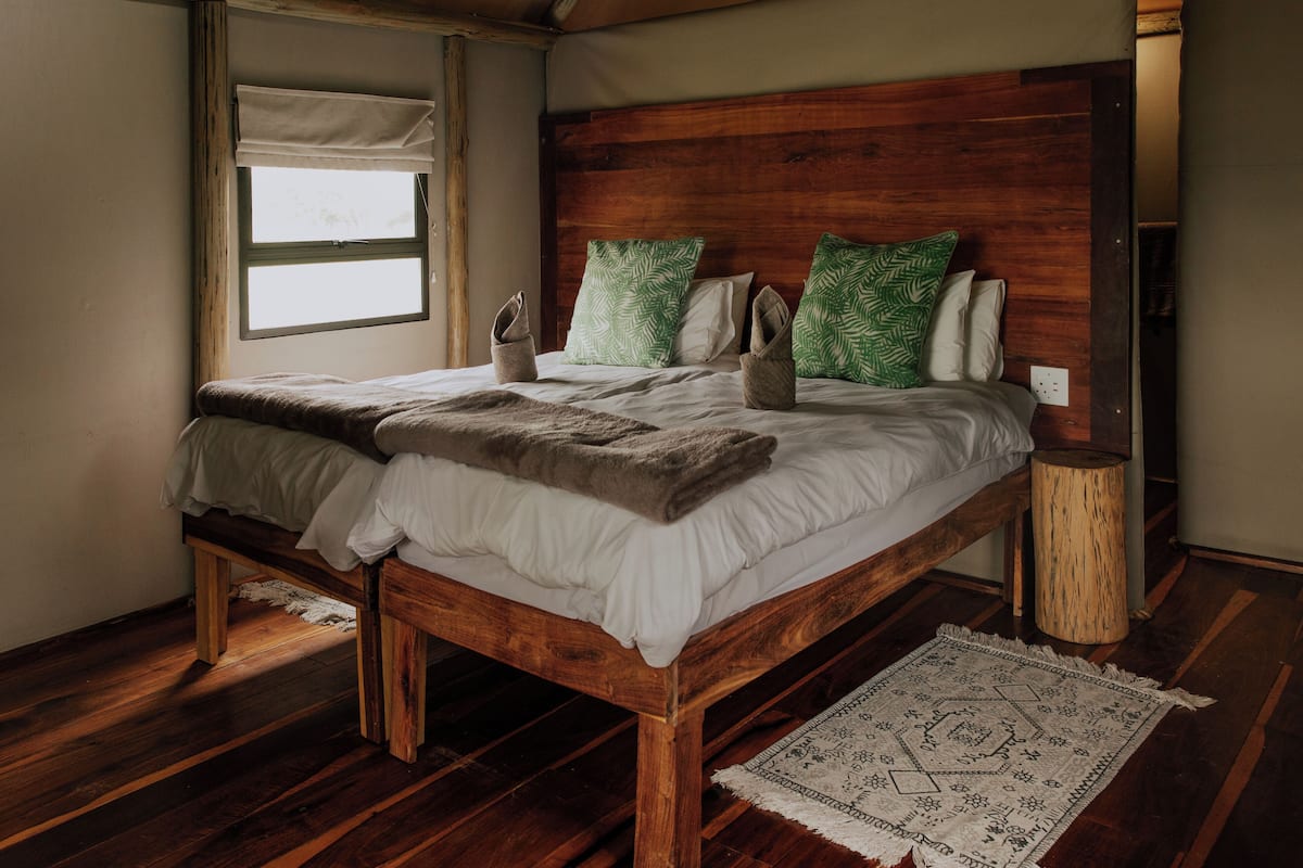 Una cama de madera con cabecera, una ventana y suelo de madera.