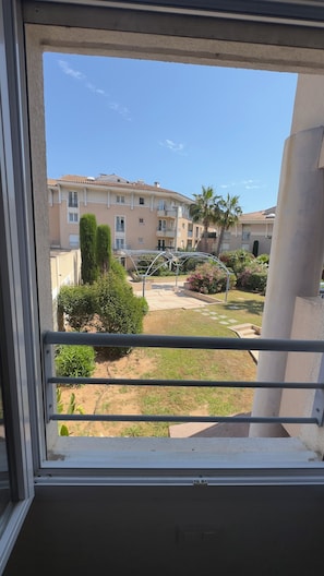 A balcony with a view of a courtyard, a pergola, and a multi-story building with balconies. - TOP-OF-THE-RANGE 38 M2 APARTMENT, LOCATED IN PORT FRÉJUS, FULLY RENOVATED TO NEW. (Fréjus)