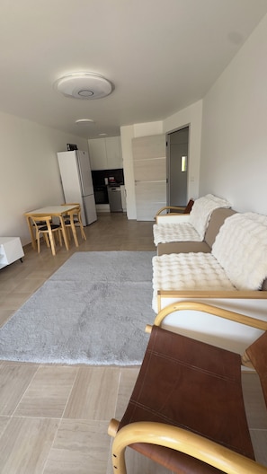 Ein modernes Wohnzimmer mit einer Couch, einem Esstisch und einer Küche im Hintergrund.