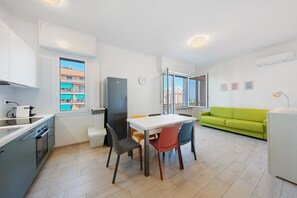 A modern kitchen with a dining table, chairs, and a green sofa in a bright living area with large windows. - Sea & Center - Chiavari Apartment with Sea View, Wi-Fi, and Air Conditioning (Chiavari)