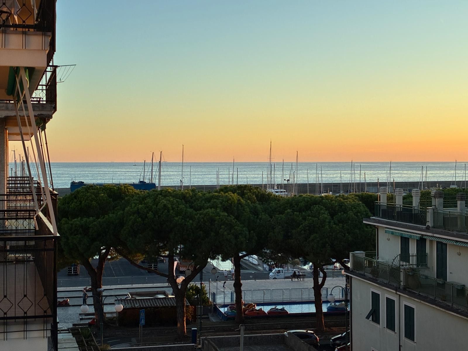 Une vue sur la côte, avec un port de plaisance, des bateaux et un ciel dégagé.