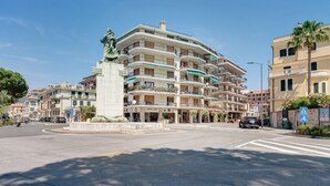 Ein mehrstöckiges Hotel mit Balkonen, einer zentralen Statue und einer Fußgängerzone.