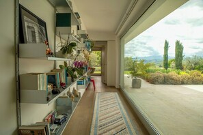 A hallway with bookshelves, a rug, and a view of greenery and mountains. - Villa among vineyards with pool near Conero (San Marcello)