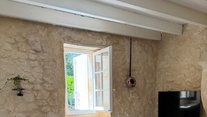 Ein Wohnzimmer mit einer Couch, einem Couchtisch, einem Fernseher und einem Fenster mit geöffnetem Klappladen.
