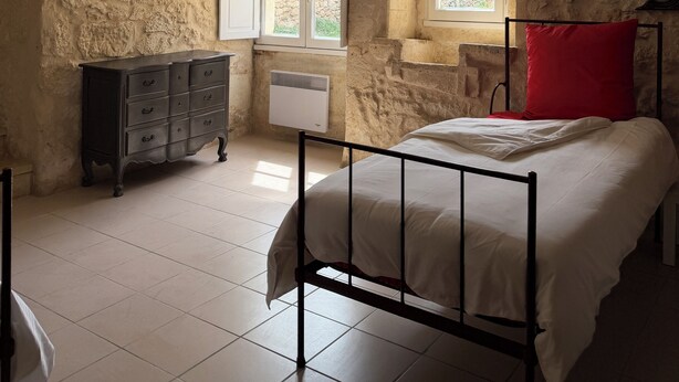 Ein Schlafzimmer mit einem Bett, einem Schminktisch, einem Fenster und einer Steinwand.