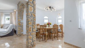 A dining area with a round table, wooden chairs, and a stone column. - Spacious 4-bedroom Villa in marvellous Pula with  outdoor kitchen and Pool (Pula)