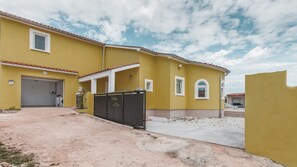 Ein gelbes Gebäude mit Garage, überdachter Auffahrt und befahrbarer Fläche.