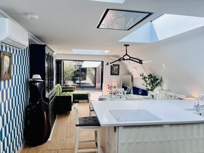 A modern kitchen with a central island, skylights, and a dining area with a view. - Beautiful Cambridge Home by Midsummer Common (Cambridgeshire)