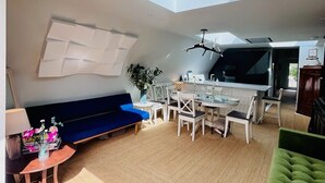 En modern inredning med ett takfönster, en matplats och olika sittgrupper.