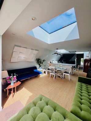 A modern interior with a skylight, a dining area, and seating arrangements. - Beautiful Cambridge Home by Midsummer Common (Cambridgeshire)