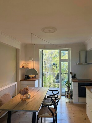 A modern kitchen with a dining area, a view through a glass door, and a small balcony. - Modern flat by the lakes in Copenhagen (København)
