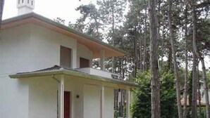 Un edificio de dos pisos con un balcón, rodeado de árboles.