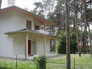 Ein zweistöckiges Gebäude mit Balkon, umgeben von Bäumen.