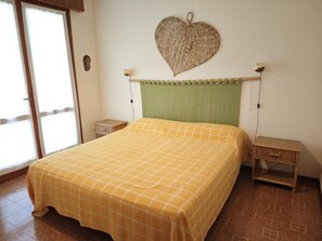 Una habitación con una cama, una mesita de noche, un cabecero verde, un adorno de corazón en la pared y un armario pequeño.