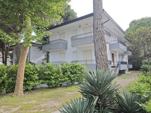 Un edificio de varios pisos con balcones, rodeado de vegetación y árboles.