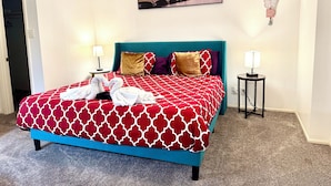 A hotel room with a bed, two bedside tables, a wall-mounted picture, and a decorative wall piece. - Medical center 2-bedroom apartment in perfect Houston with cool AC and comfort (Houston)