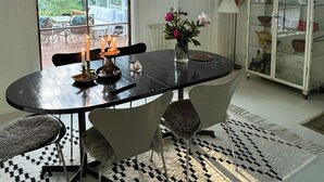 Een eetgedeelte met een ronde tafel, stoelen, kaarsen, een vaas met bloemen en een kast met glazen deuren.