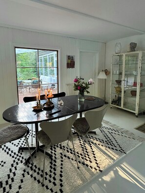 Ein Essbereich mit einem runden Tisch, Stühlen, Kerzen, einer Blumenvase und einem Schrank mit Glastüren.