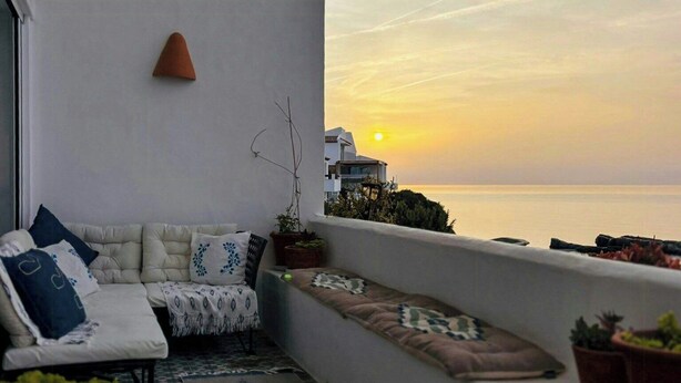 A balcony with a sofa, cushions, a small table, and potted plants. - Designer duplex facing the sea in Estepona (Estepona)