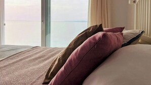 A hotel room with a bed, a window with curtains, and a view of the sky. - Designer duplex facing the sea in Estepona (Estepona)