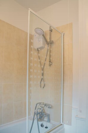 Een douche met een handdouche en een kraan die aan de muur bevestigd is.