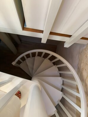 A spiral staircase with white railings and wooden beams.