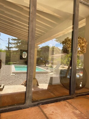 Una casa moderna con puerta de cristal, piscina y terraza cubierta.