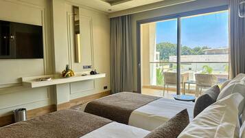 Habitación de hotel con dos camas, televisión, minibar y balcón con vistas.