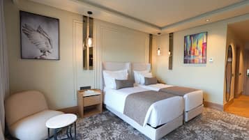 Een hotelkamer met een tweepersoonsbed, nachtkastje, stoel en kunst aan de muur.
