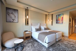 A hotel room with a double bed, a bedside table, a chair, and artwork on the walls. - Grand Dominium (Agadir)