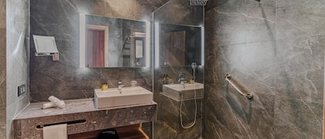 Ein modernes Badezimmer mit einer Duschkabine aus Glas, zwei Waschbecken und einem Waschtisch mit Handtuchhalter.