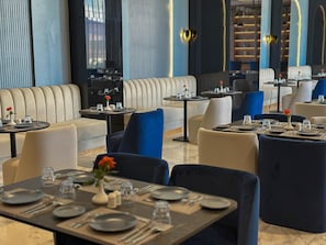 A restaurant with booths and tables, some with blue chairs, and a modern interior design. - Grand Dominium (Agadir)