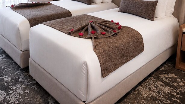 Habitación de hotel con dos camas, un cuadro grande y una lámpara moderna.