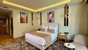 Habitación de hotel con una cama grande, mesitas de noche, una silla y obras de arte en las paredes.