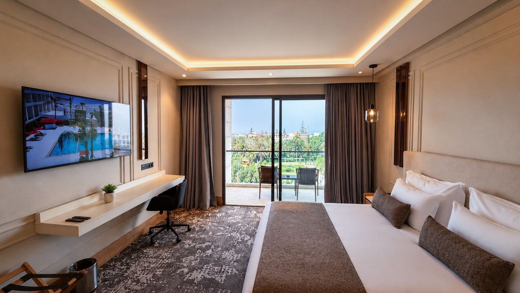 Habitación de hotel con una cama grande, un escritorio con silla, televisión y balcón con vistas.