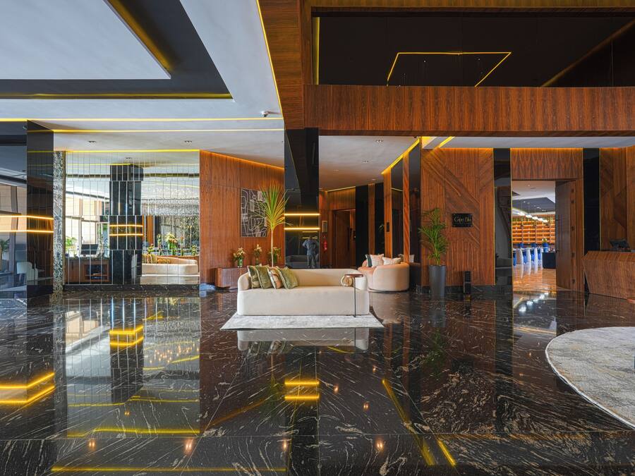 A modern lobby with a marble floor, wooden accents, and a reception desk.
