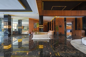 Eine moderne Lobby mit Marmorboden, Holzelementen und einer Rezeption.